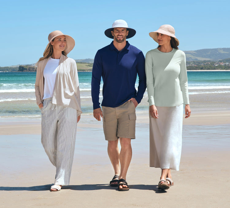 Three people standing on a beach with ocean and sky in the background wearing Solbari sun hats and sun protective clothing.
