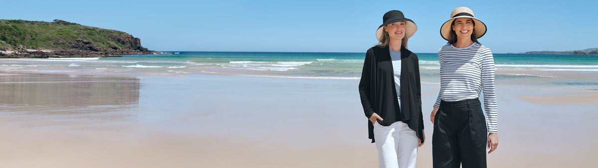 Two people standing on a beach with ocean and sky in the background
