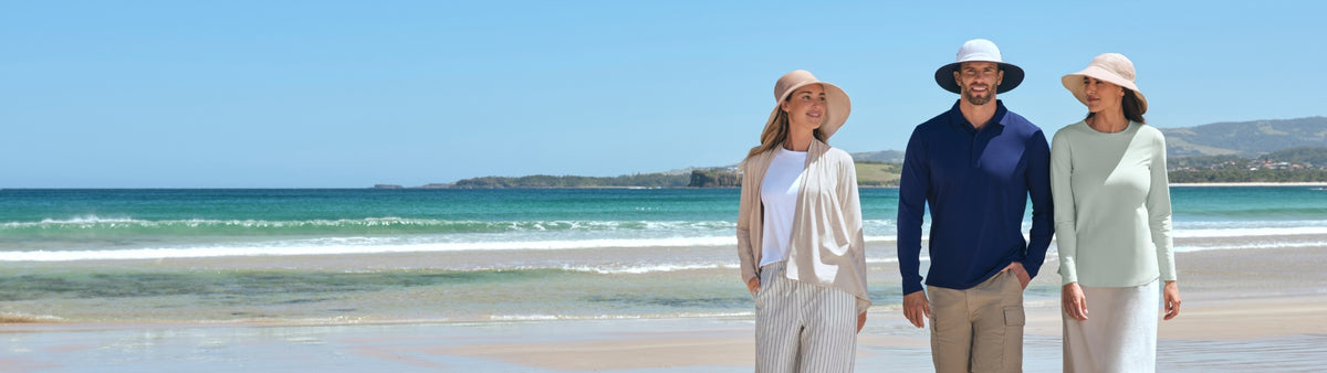 Three people standing on a beach with ocean and clear sky in the background